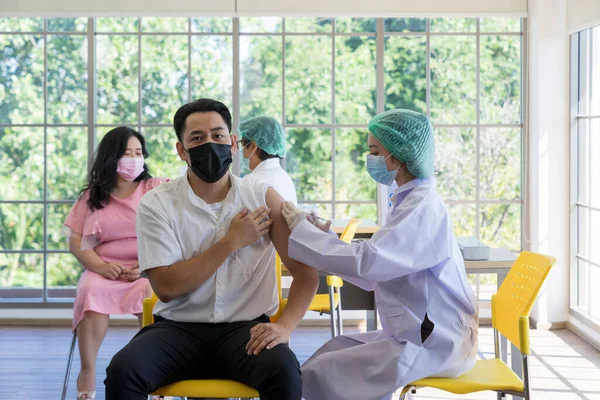 Bir doktor Coronavirüs salgınını önlemek için hastanedeki Asyalılara kovid 19 aşısı enjekte ediyor. Bağışıklık sistemi, Covid-19 aşı kliniği, Coronavirus küresel salgını.