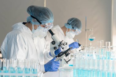 Kadın bilim adamları kovid 19 virüs aşısını tıbbi bir laboratuvarda araştırmak için mikroskop kullanıyorlar. Bir doktor kimya laboratuvarında koronavirüsü araştırmak için biyoteknoloji kullanır. İlaç bilimi kavramları