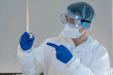 Aşıyı kapat. Laboratuvarda Koronavirüs aşısı şişesi tutan Asyalı bir bilim adamı. Laboratuvarda Covid-19 aşısını araştıran ve icat eden Virologların başarısı. Genel Salgın 2019-202