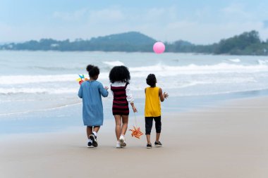 Sevimli Afrikalı Amerikalı çocuk el ele tutuşup tropikal plajda fırıldak oynuyor. Bir grup çocuk yazın deniz kıyısında tatilde eğleniyor. Yaz tatili.