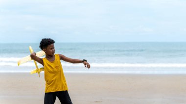 Afrika kökenli Amerikalı çocukların portresi yaz tatilinde tropikal plajda uçak oyuncağı oynuyor. Plaj tatillerinde koşan neşeli çocuk. Fotokopi alanı ile Hayal, Özgürlük, Başarı hedefleri