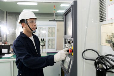 Asyalı teknisyen, CNC fabrika kesme makinesi imalat atölyesinde çalışıyor. İş gününde metal fabrikasındaki torna makinesini denetleyici ya da işçi denetimi.