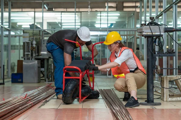 Beyaz kadın endüstriyel mühendis, iş gününde motosiklet fabrikasında çalışan profesyonel teknisyen ile birlikte motosiklet iskeletinin bir parçasını monte etti. Sektör işyeri cinsiyet eşitliği.