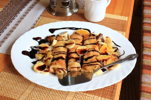 Блинчики с манной крупой, бананами и апельсинами, пропитанные тёмным шоколадом — стоковое фото