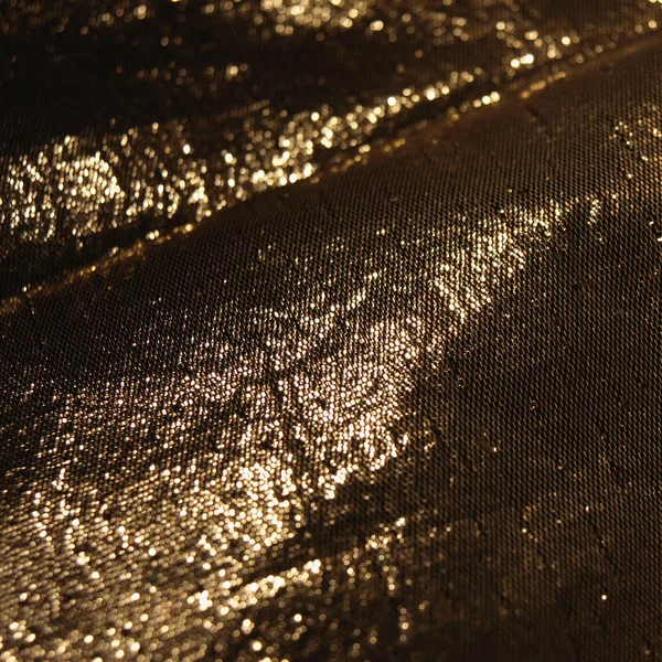 Gedetailleerde textuur van gouden stof in het donker — Stockfoto