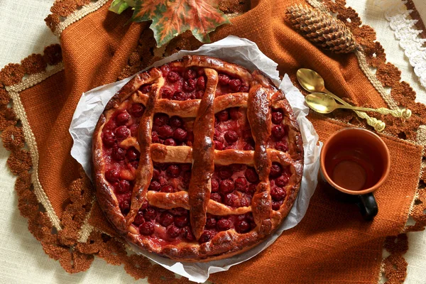 Still Life: Vintage Homemade cherry pie and cup of coffee on dark brown table cloth decorated with autumn leaves — Stock Photo, Image