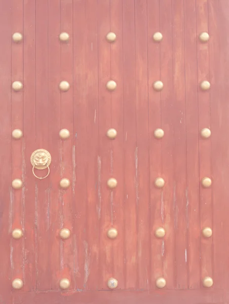 ビンテージ スタイルのライオン ドアノッカーと古代の赤い木製の門 — ストック写真