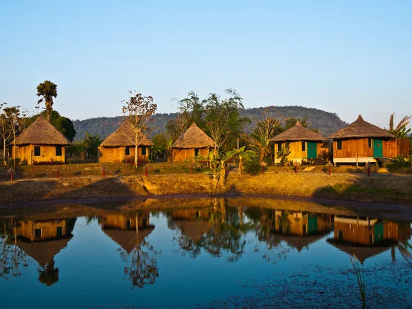 Bamboo cottages and its reflection in pond in Thailand