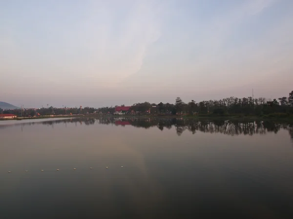 Manhã pausas sobre o glassy ainda lago e árvore fundo — Fotografia de Stock