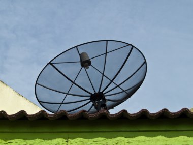 Bir uydu çanağı bir çatı ve mavi gökyüzü arka plan üzerinde 