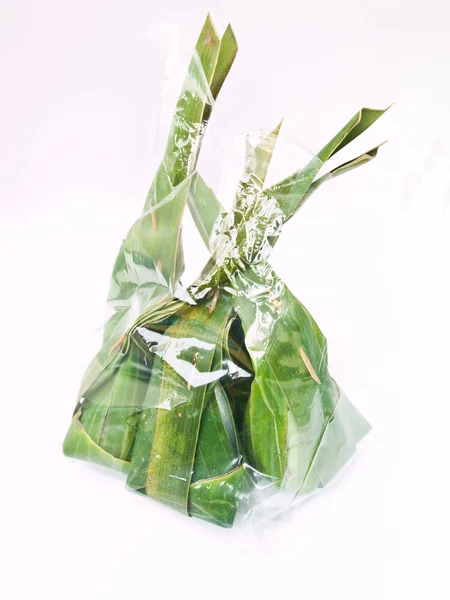由孤立的白色背景上的透明塑料袋中的香蕉叶制成的泰国甜点包 — 图库照片