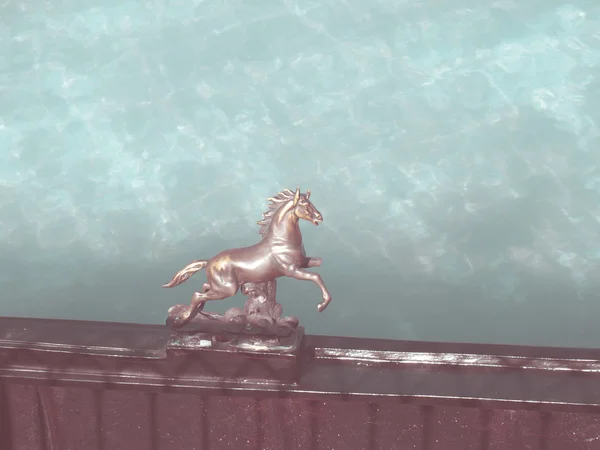 Bronshästen staty på staket med turkost vatten bakgrund i vintage stil — Stockfoto