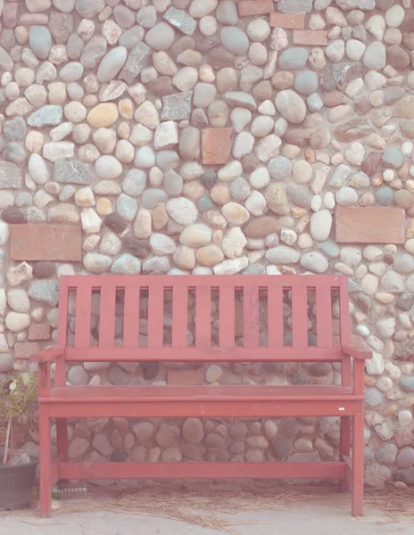 Red wooden bench and stone wall background in vintage style — Stock Photo, Image