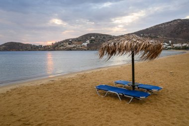 Ios Adası 'ndaki Chora' nın kumlu sahilinde güneşli şezlonglu saman şemsiyesi. Cyclades, Yunanistan