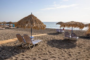 Santorini, Yunanistan - 16 Eylül 2020: Santorini, Cyclades, Yunanistan 'ın güneyindeki Vlychada Plajı' nda güneşli saman şemsiyeler