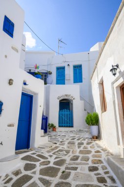 Paros Adası 'ndaki Lefkes köyünde beyazlatılmış caddede mavi pencereli ve kapısı olan tipik bir Yunan evi. Cyclades, Yunanistan