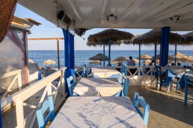 Santorini, Yunanistan - 16 Eylül 2020: Santorini adasındaki bir kasaba olan Perissa 'daki Black Beach' teki restoranda masalar. Cyclades, Yunanistan