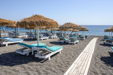 Santorini, Yunanistan - 17 Eylül 2020: Santorini adasındaki Perissa 'nın siyah volkanik kumlu plajında güneşleniyor. Cyclades, Yunanistan