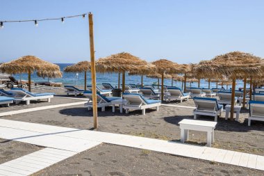 Santorini, Yunanistan - 17 Eylül 2020: Santorini adasındaki Perissa 'nın siyah volkanik kumlu plajında güneşleniyor. Cyclades, Yunanistan