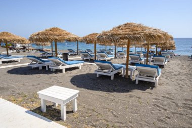 Santorini, Yunanistan - 17 Eylül 2020: Santorini adasındaki Perissa 'nın siyah volkanik kumlu plajında güneşleniyor. Cyclades, Yunanistan