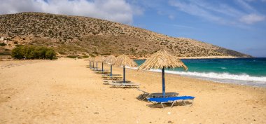 Ios Adası 'ndaki Agia Theodoti plajında güneş yatakları ve şemsiyeler. Altın kumu ve masmavi suları olan harika bir sahil. Cyclades, Yunanistan