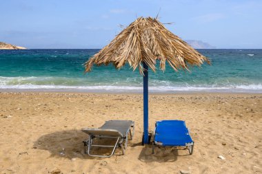 Ios Adası 'ndaki Agia Theodoti plajında güneş yatakları ve şemsiye. Altın kumu ve masmavi suları olan harika bir sahil. Cyclades, Yunanistan