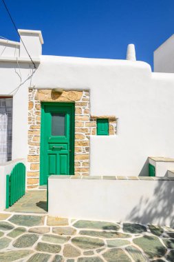 Folegandros Adası, Cyclades, Yunanistan 'daki güzel Chora kasabasında, beyaz kapılı sokağa yeşil kapılı bina.