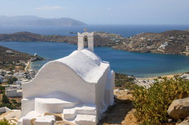 A small white chapel on the top of a hill in the city center of Chora on Ios Island. View of the bay and the Aegean Sea. Cyclades, Greece