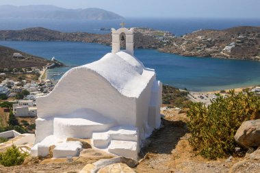 A small white chapel on the top of a hill in the city center of Chora on Ios Island. View of the bay and the Aegean Sea. Cyclades, Greece