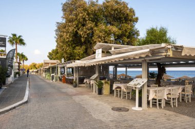 Santorini, Yunanistan - 18 Eylül 2020: Santorini 'deki Kamari tatil beldesinde deniz kenarında gezinti. Cyclades Adaları