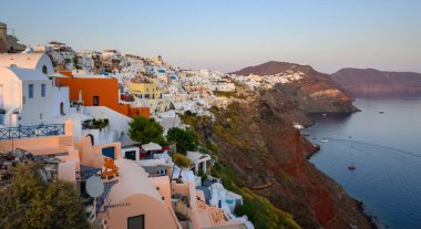 Santorini, Yunanistan - 17 Eylül 2020: Oia köyündeki Santorini adasının kıyıları gün batımında, Kiklad, Yunanistan