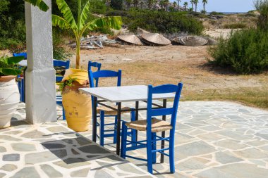 Ios, Yunanistan - 21 Eylül 2020: Ios Adası 'ndaki Manganari plajındaki Yunan restoranında masa ve sandalyeler. Cyclades, Yunanistan