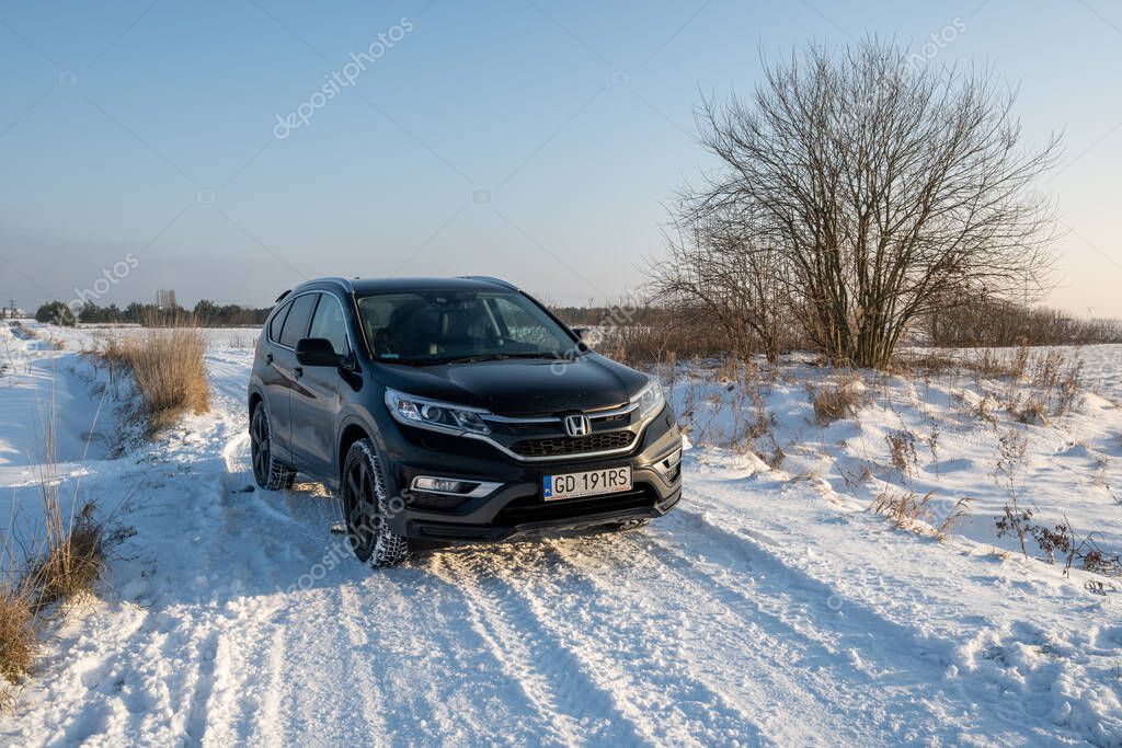 Puck, Poland - January 17, 2021: Black Honda CR-V car on a snowy rural road.