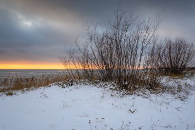 Gün batımında kumsalı kaplayan kar, Hel Yarımadası kıyısında Jastarnia 'da kış manzarası. Polonya