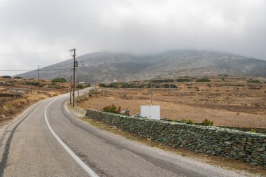 Bulutlu bir günde Folegandros adasında asfalt yol. Dağlık ve kırsal alan. Cyclades, Yunanistan