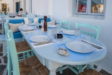 Paros, Yunanistan - 27 Eylül 2020: Paros Adası 'ndaki güzel Naoussa limanındaki sahil restoranında masa ve sandalyeler. Cyclades, Yunanistan