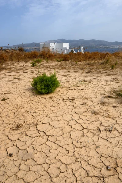 Dry and cracked ground. Greek summer villa in background