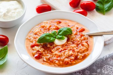 Krema ve fesleğenle süslenmiş pilavlı domates çorbası..