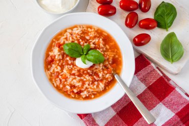 Krema ve fesleğenle süslenmiş pilavlı domates çorbası..