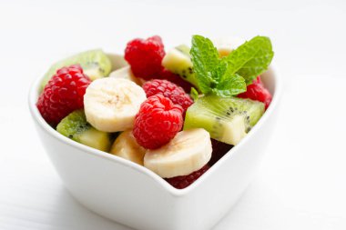 Beyaz arka planda kasede sağlıklı taze meyve salatası.