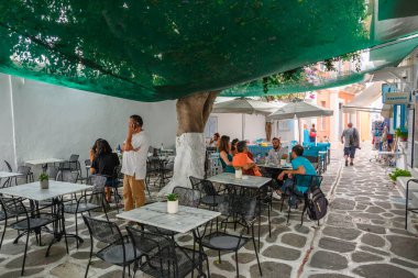 Paros, Yunanistan - 28 Eylül 2020: Paros adasındaki Parikia kasabasındaki ağaçların gölgesindeki Yunan restoranı.