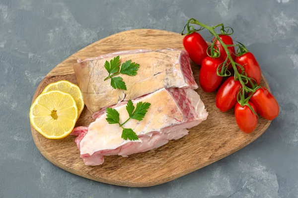 Fresh uncooked catfish with vegetables on wooden board.