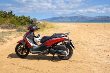 Paros, Yunanistan - 30 Eylül 2020: Paros adasındaki plajda motosiklet. Motosiklet Yunanistan 'da popüler bir ulaşım aracıdır.