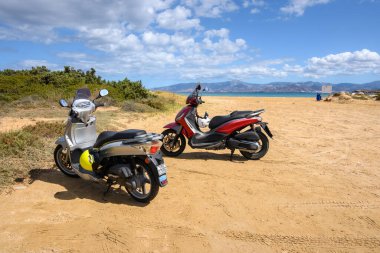 Paros, Yunanistan - 30 Eylül 2020: Paros adasındaki plajda motosikletler. Motosiklet Yunanistan 'da popüler bir ulaşım aracıdır.