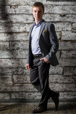 Bir gri takım elbise ve stüdyo çekim üzerinde tam uzunlukta önünde ışık gömlek duran genç bir adam