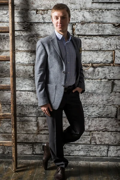 Mladý muž v šedém obleku a lehká košile postavení v celé délce na studio natáčení — Stock fotografie