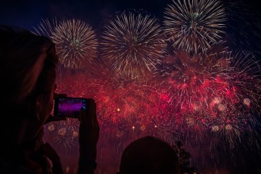 Shoot photos and video to your smartphone: Colorful fireworks in the sky over the park in Moscow on the banks of the river clipart