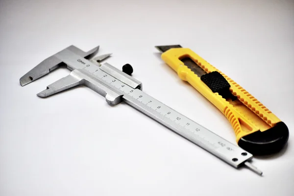 Callipers and yellow stationery knife — Stock Photo, Image