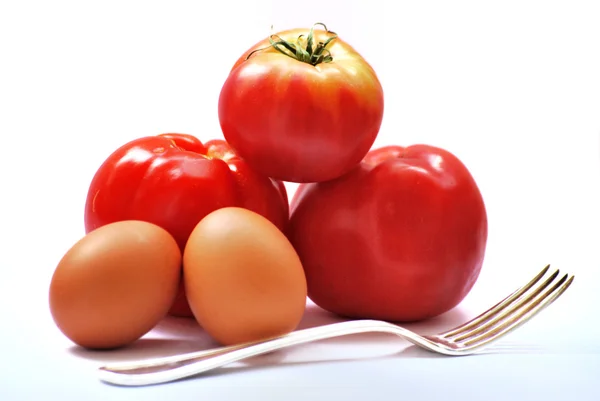 Pochi pomodori e uova sul tavolo con una forchetta e una pentola di spezie — Foto Stock