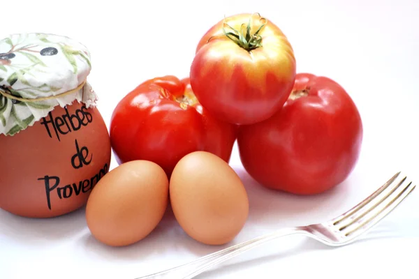 Pochi pomodori e uova sul tavolo con una forchetta e una pentola di spezie — Foto Stock